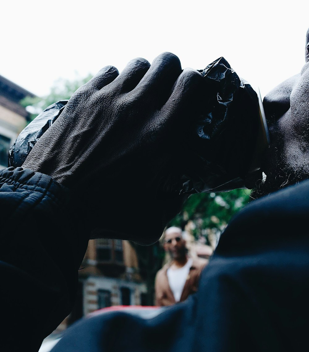 a man in a black jacket is holding his hand up to his face