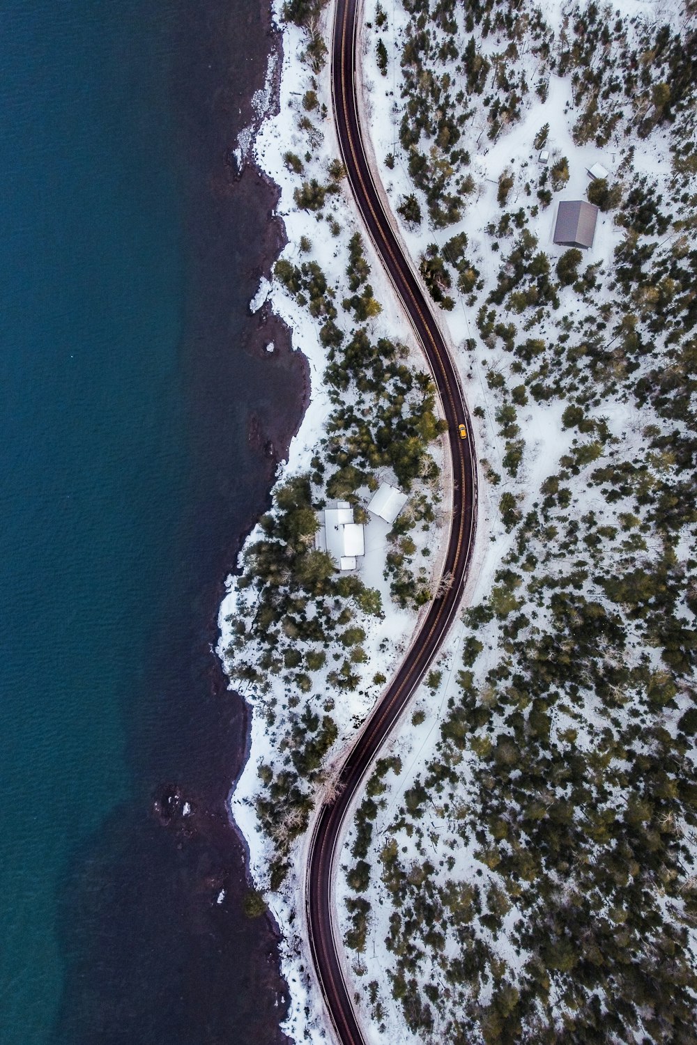 an aerial view of a winding road next to a body of water