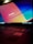A laptop keyboard is visible with an open screen displaying a blurred multicolored desktop background. The colors are vivid, with prominent shades of blue, orange, and red. An Intel sticker is in focus on the laptop's palm rest area.
