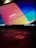 A laptop keyboard is visible with an open screen displaying a blurred multicolored desktop background. The colors are vivid, with prominent shades of blue, orange, and red. An Intel sticker is in focus on the laptop's palm rest area.