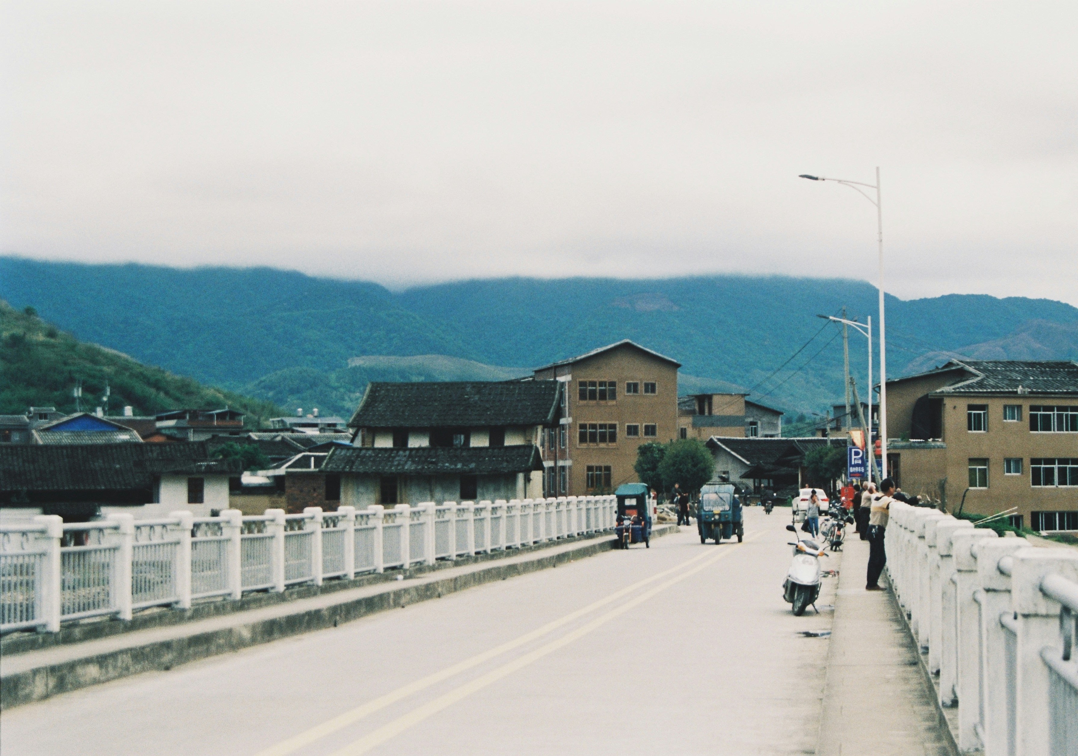 a group of people riding scooters across a bridge