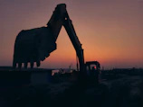 Close-up shot of heavy machinery operating on a large infrastructure project at sunset.