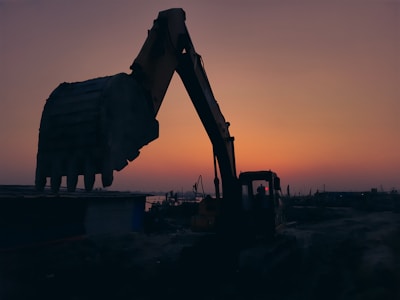 Sunset view over the excavation site with machinery silhouettes.