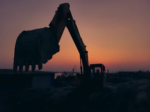 Close-up shot of heavy machinery operating on a large infrastructure project at sunset.