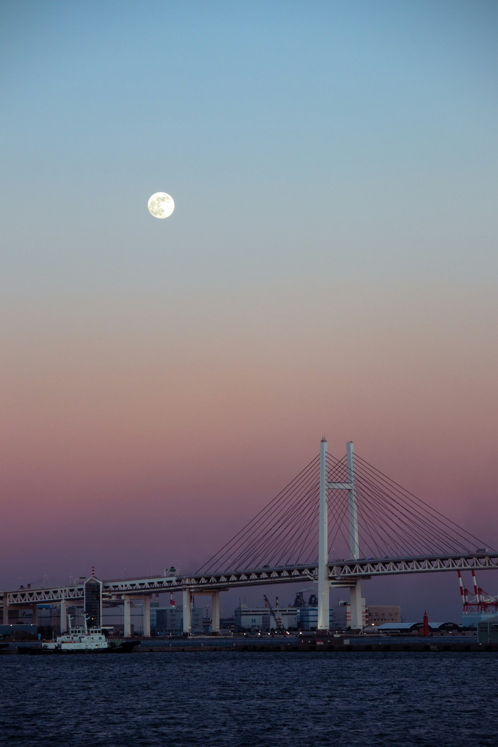 a full moon rising over a bridge over a body of water