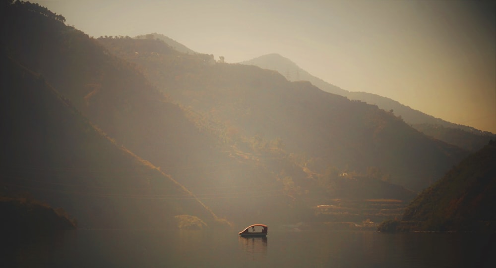 a boat floating on top of a lake surrounded by mountains