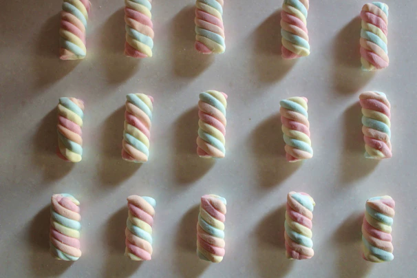 Close-up of fluffy handcrafted marshmallows in pastel colors arranged on a rustic wooden board.