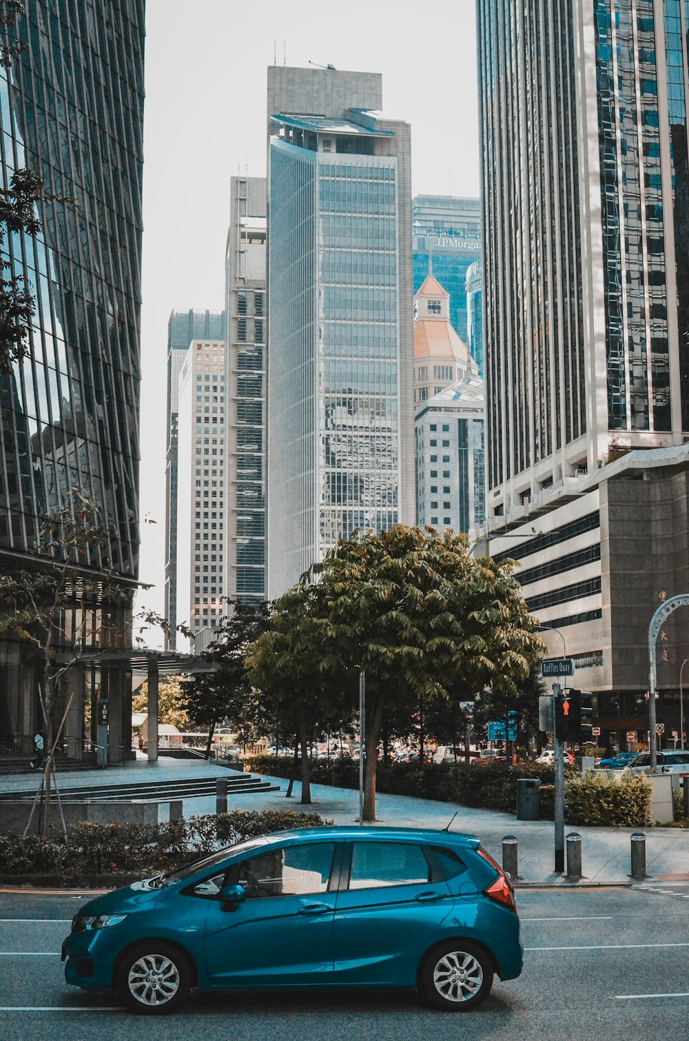 a blue car parked in a parking lot in front of tall buildings