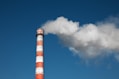a red and white smokestack with a blue sky in the background
