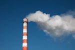 a red and white smokestack with a blue sky in the background