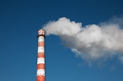a red and white smokestack with a blue sky in the background