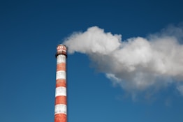 a red and white smokestack with a blue sky in the background