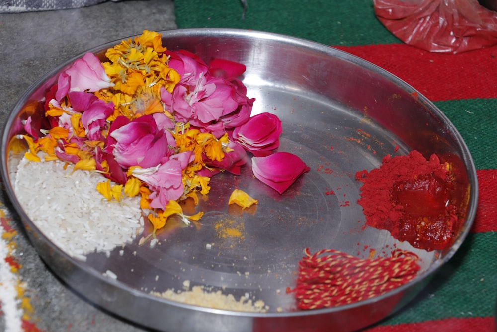 a metal bowl filled with flowers on top of a table