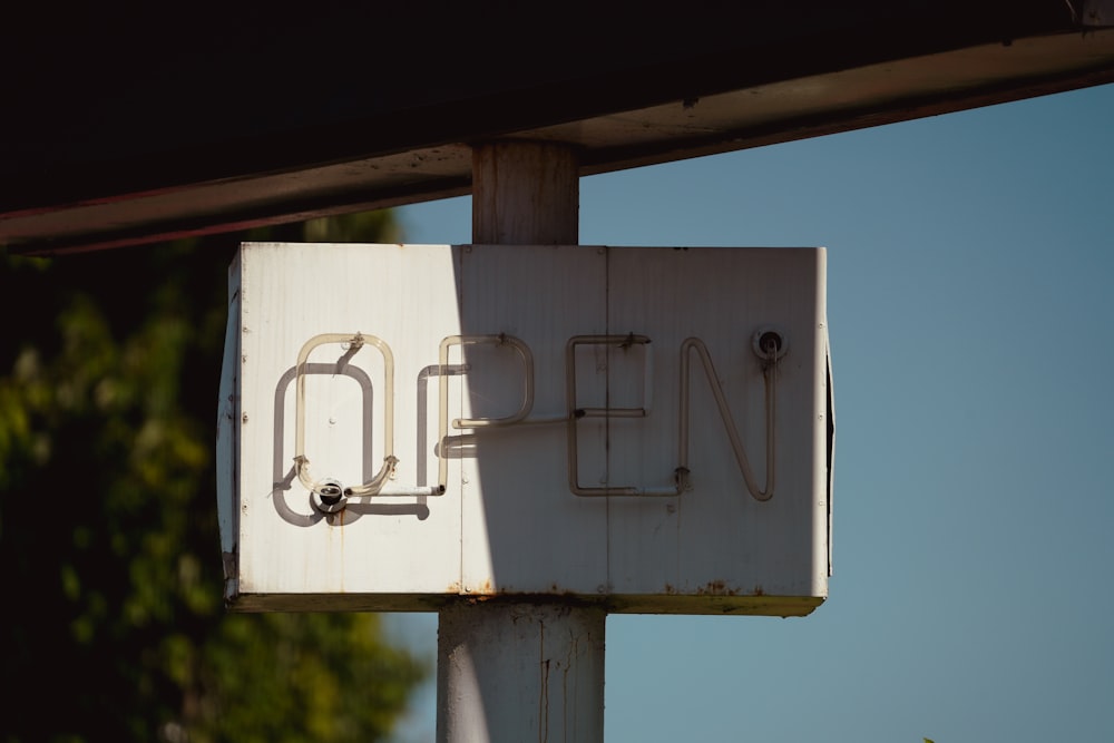 a close up of a sign with trees in the background