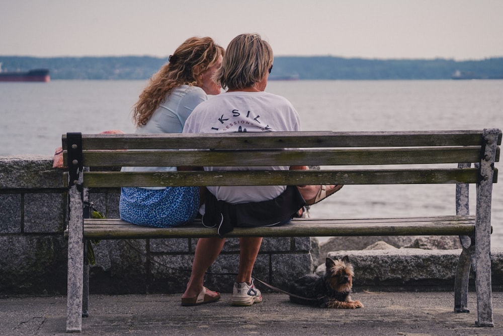 a man and woman sitting on a bench next to a dog