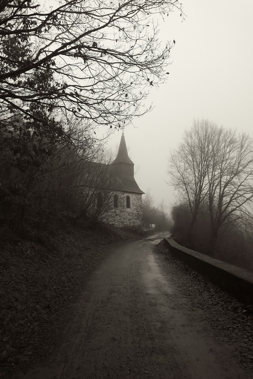 a black and white photo of a church on a foggy day
