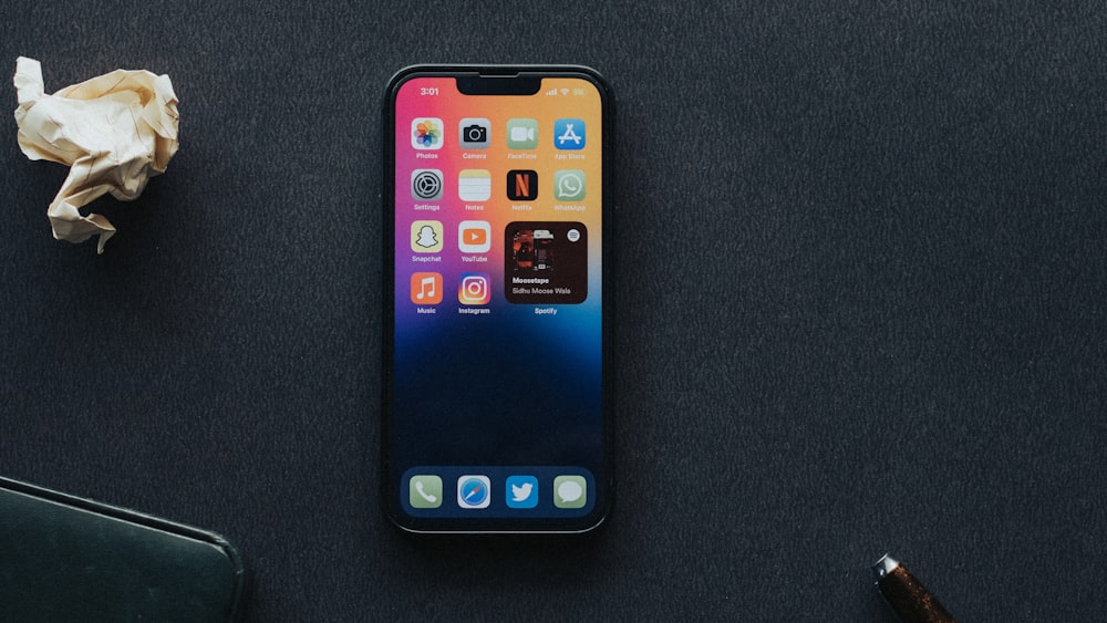 a cell phone sitting on top of a table next to a pen