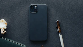 a cell phone sitting on top of a table next to a pen