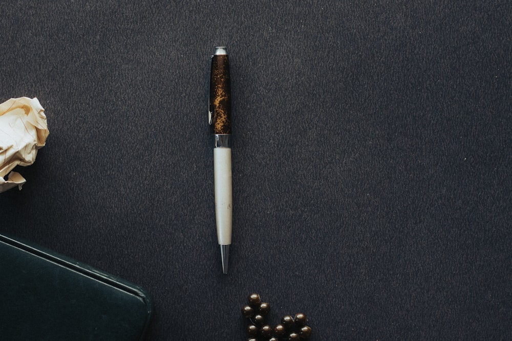 a pen sitting on top of a table next to a flower