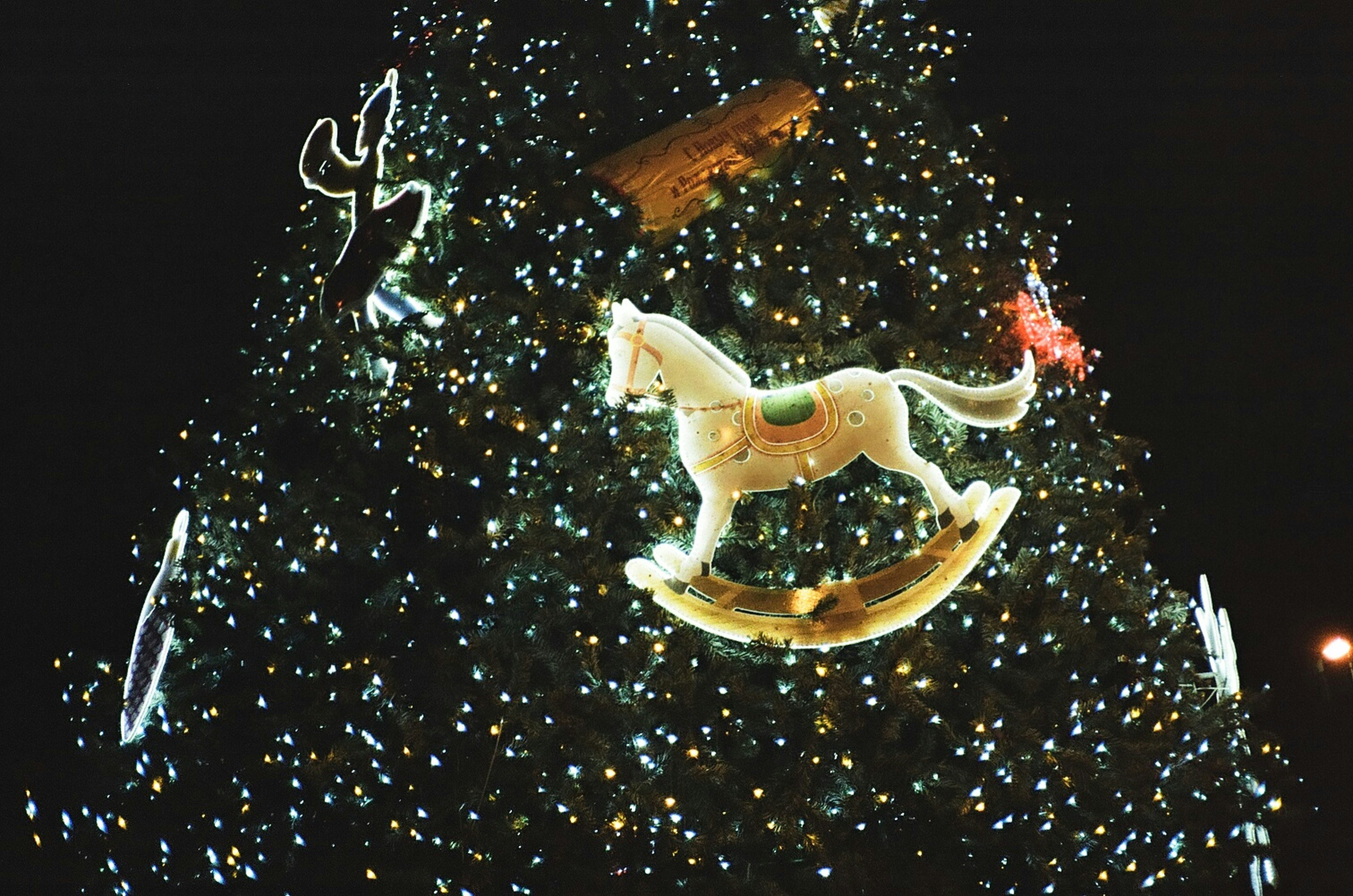 a lighted christmas tree with a rocking horse on it