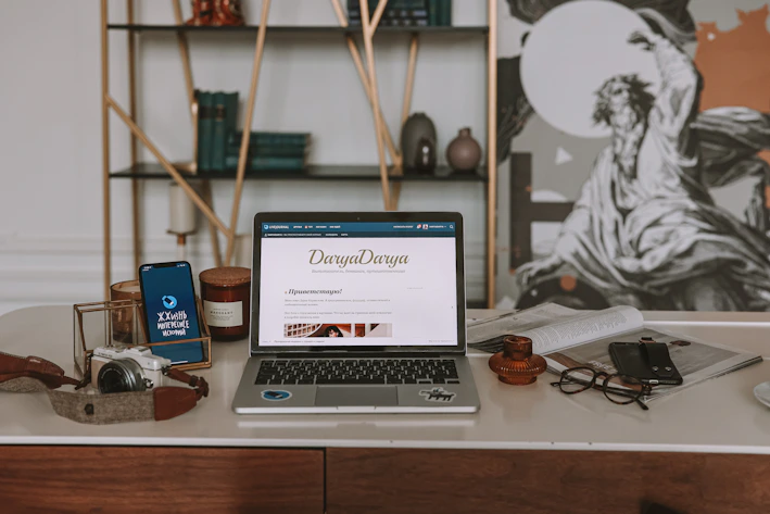 A serene workspace with a laptop displaying an e-book cover surrounded by calming candles and crystals.