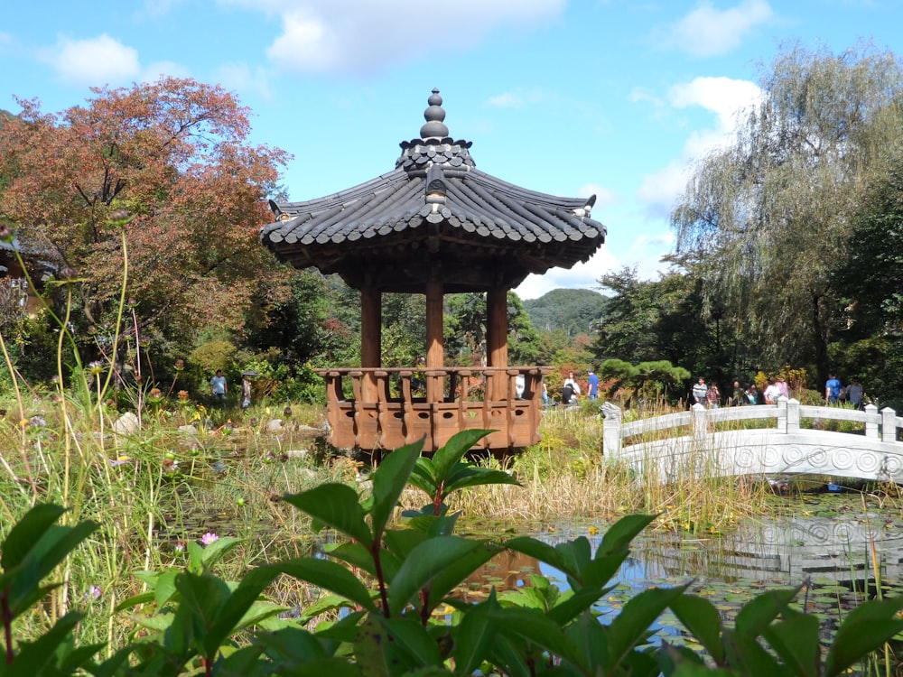 a gazebo in a park with a bridge in the background