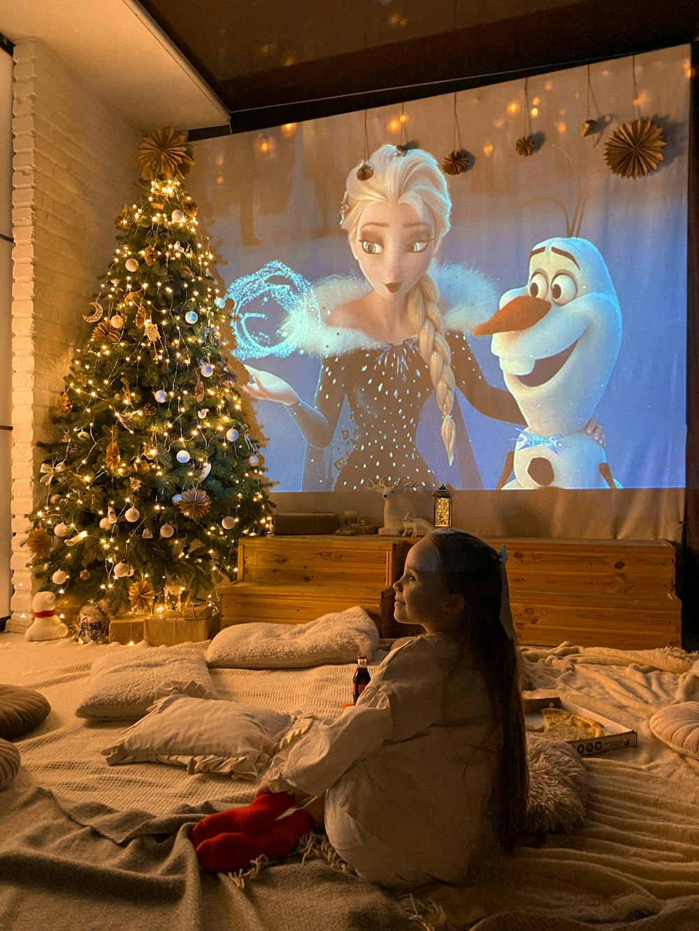 a little girl sitting on a bed watching a movie