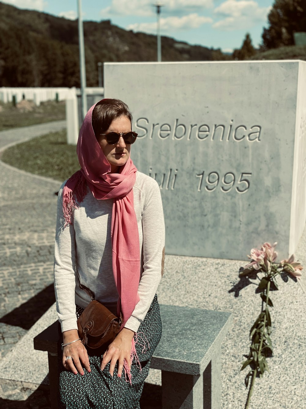 a woman sitting on a bench in front of a memorial