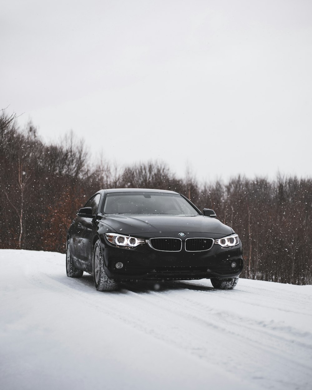 a black car driving down a snow covered road