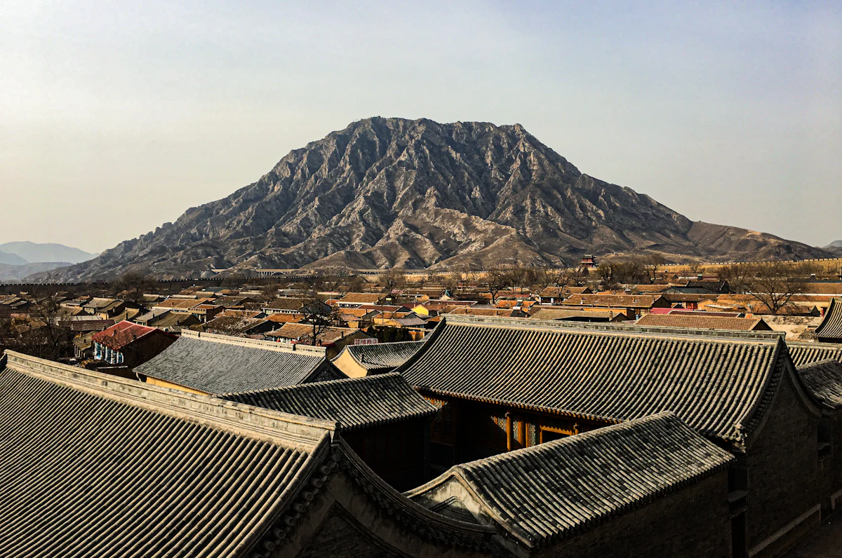 Grey tiled roofs of old courtyard houses in Zhangjiakou, with a bare rocky mountain behind