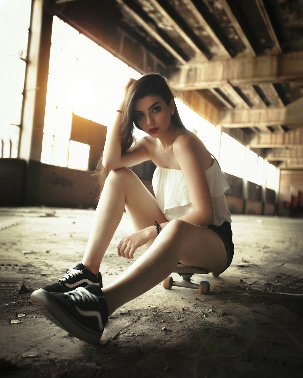 a woman sitting on a skateboard in an empty room