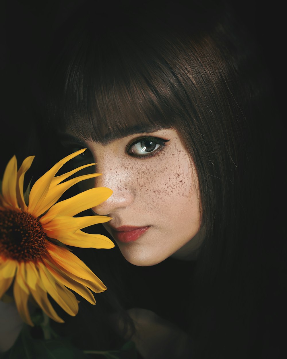 a woman holding a sunflower in front of her face