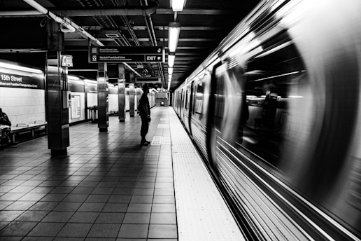 a subway station with a person standing on the platform