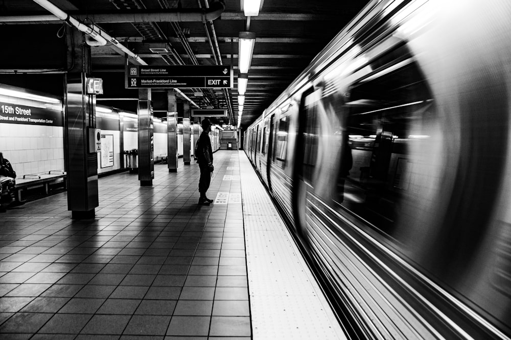 a subway station with a person standing on the platform