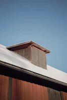 Rustic wooden barn with livestock sheltering inside on a crisp morning.