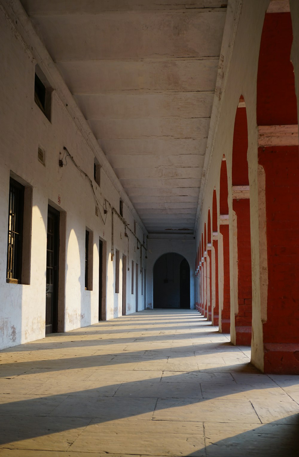 a long hallway with white walls and red pillars