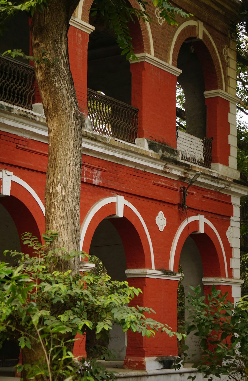 a red building with arches and a tree in front of it