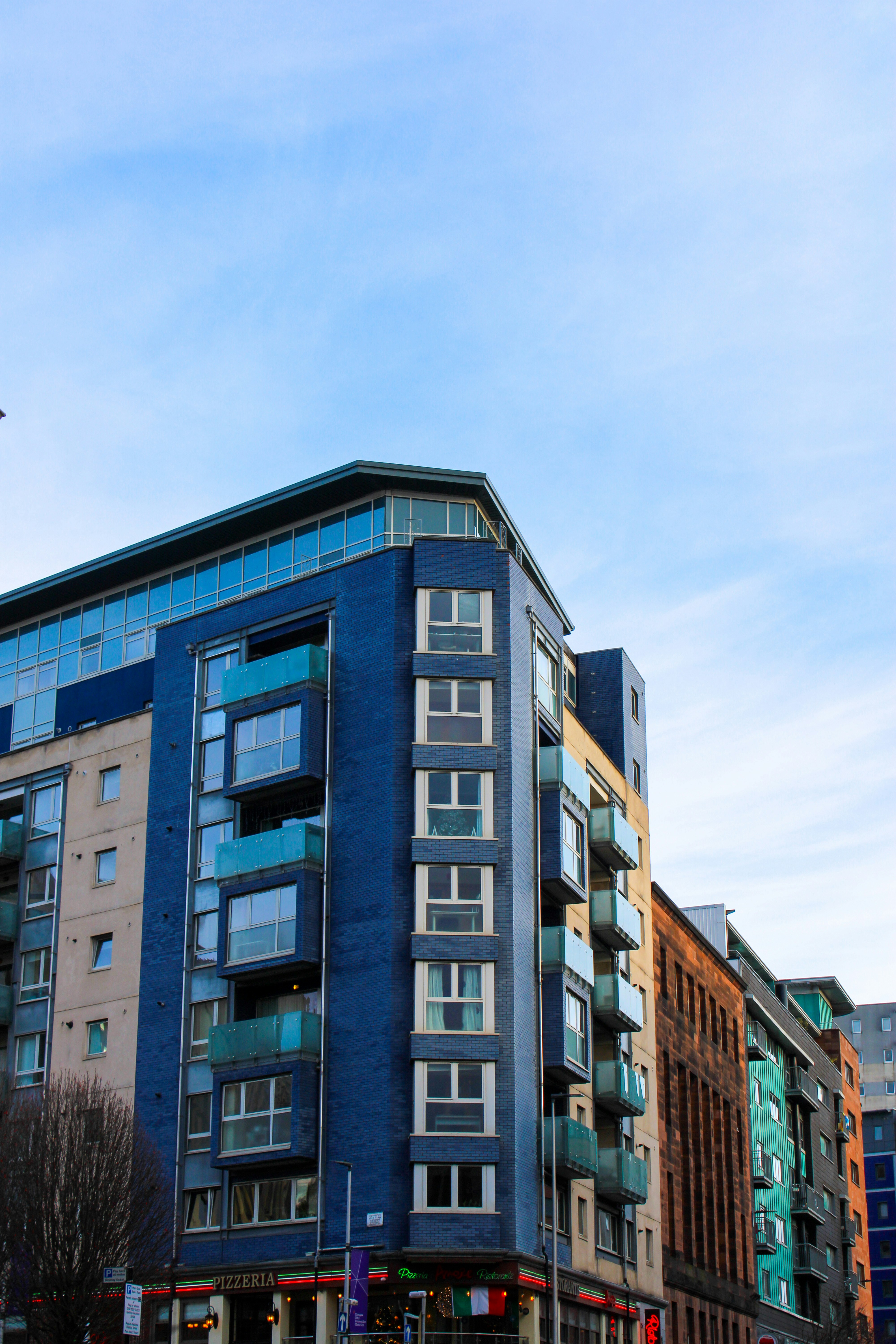 Modern luxury apartment building with glass facade and blue sky background