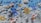A digital or voxel art scene featuring rockets, stylized coins, and abstract symbols against a three-dimensional pixelated blue and gray background. The rockets appear to have pixelated flames and are flying among coins and geometric shapes.