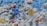 A digital or voxel art scene featuring rockets, stylized coins, and abstract symbols against a three-dimensional pixelated blue and gray background. The rockets appear to have pixelated flames and are flying among coins and geometric shapes.