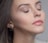 A close-up of a radiant woman showcasing flawless makeup with a soft, elegant background.