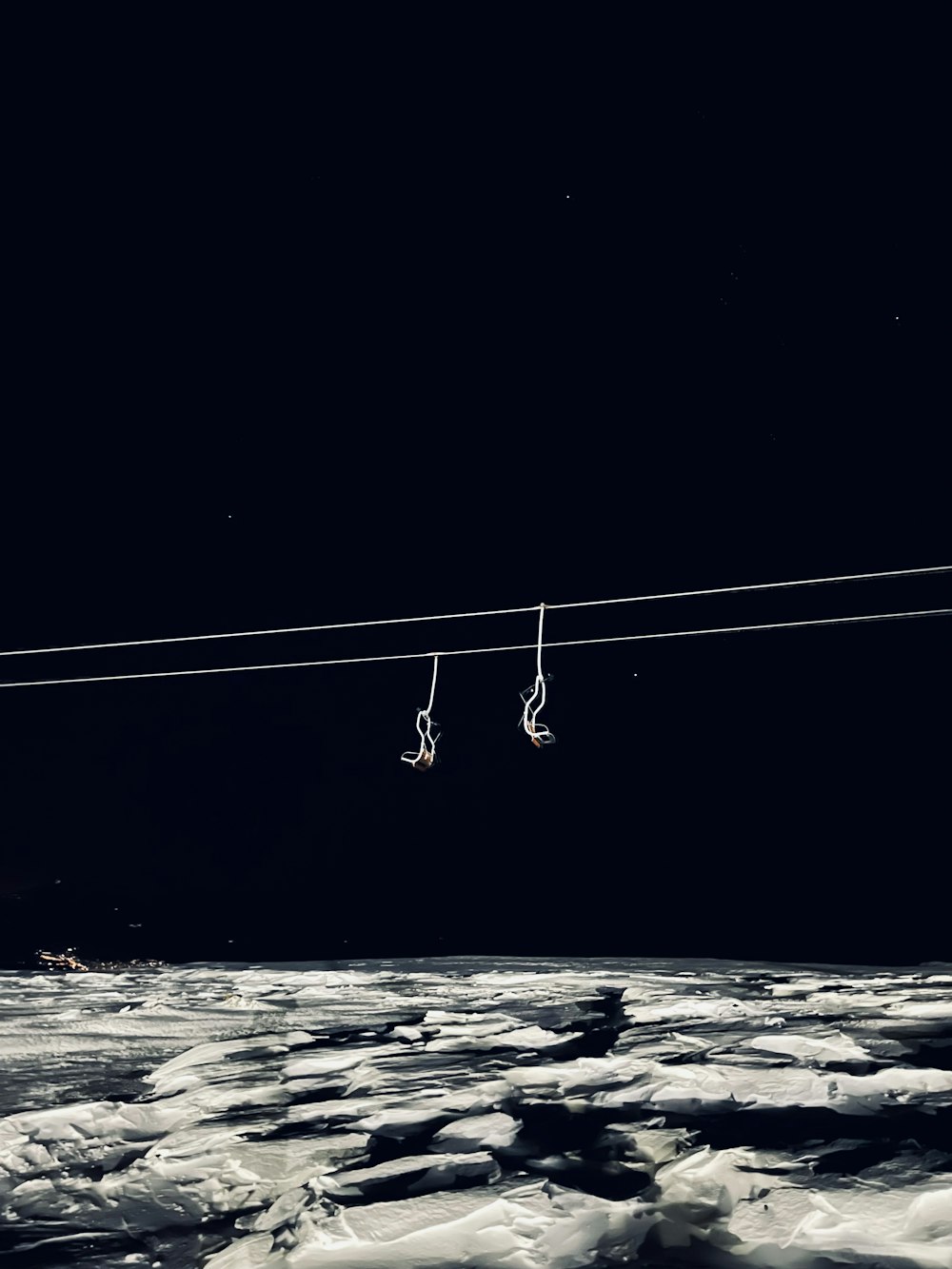 a pair of skis hanging from a wire in the snow