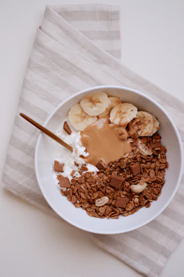 Dark Chocolate Nutronergy peanut butter swirled in a bowl with a rustic wooden spoon.