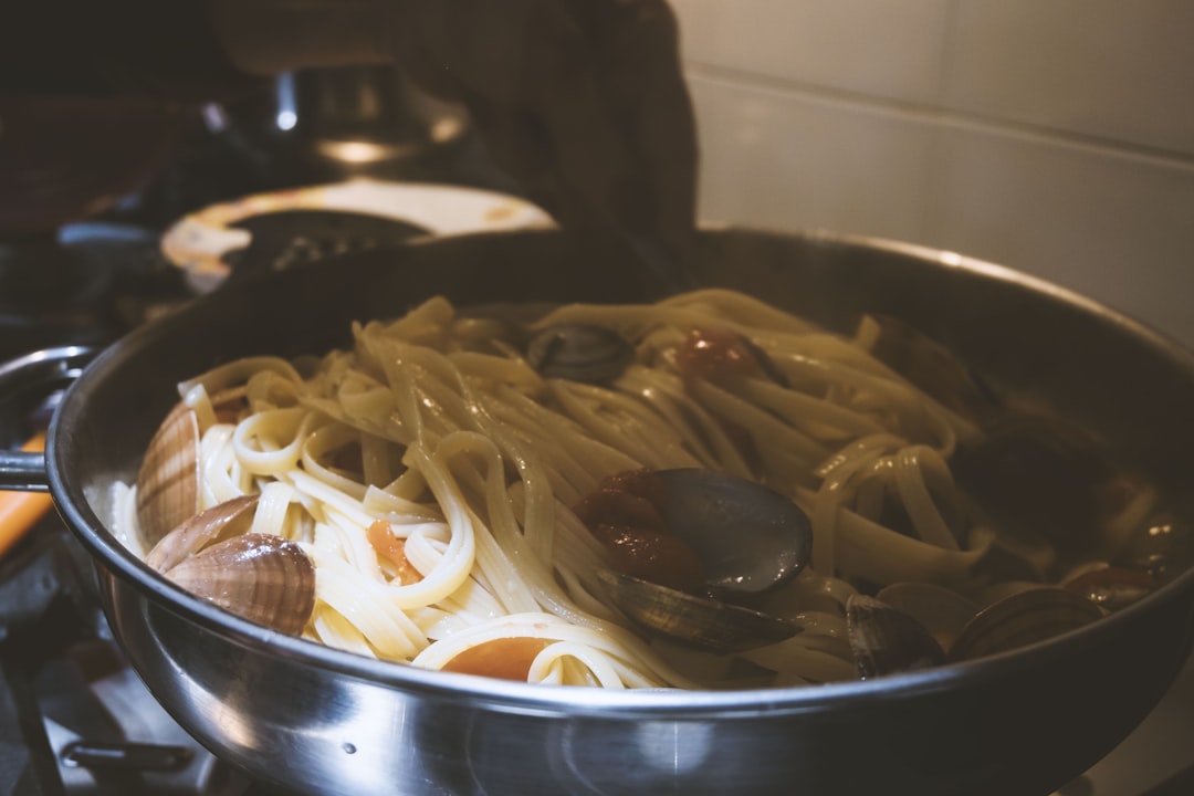 a pan filled with pasta on top of a stove, spaghetti with clams