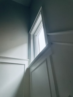 Elegant white wainscoting panels framing a cozy living room corner bathed in natural light.