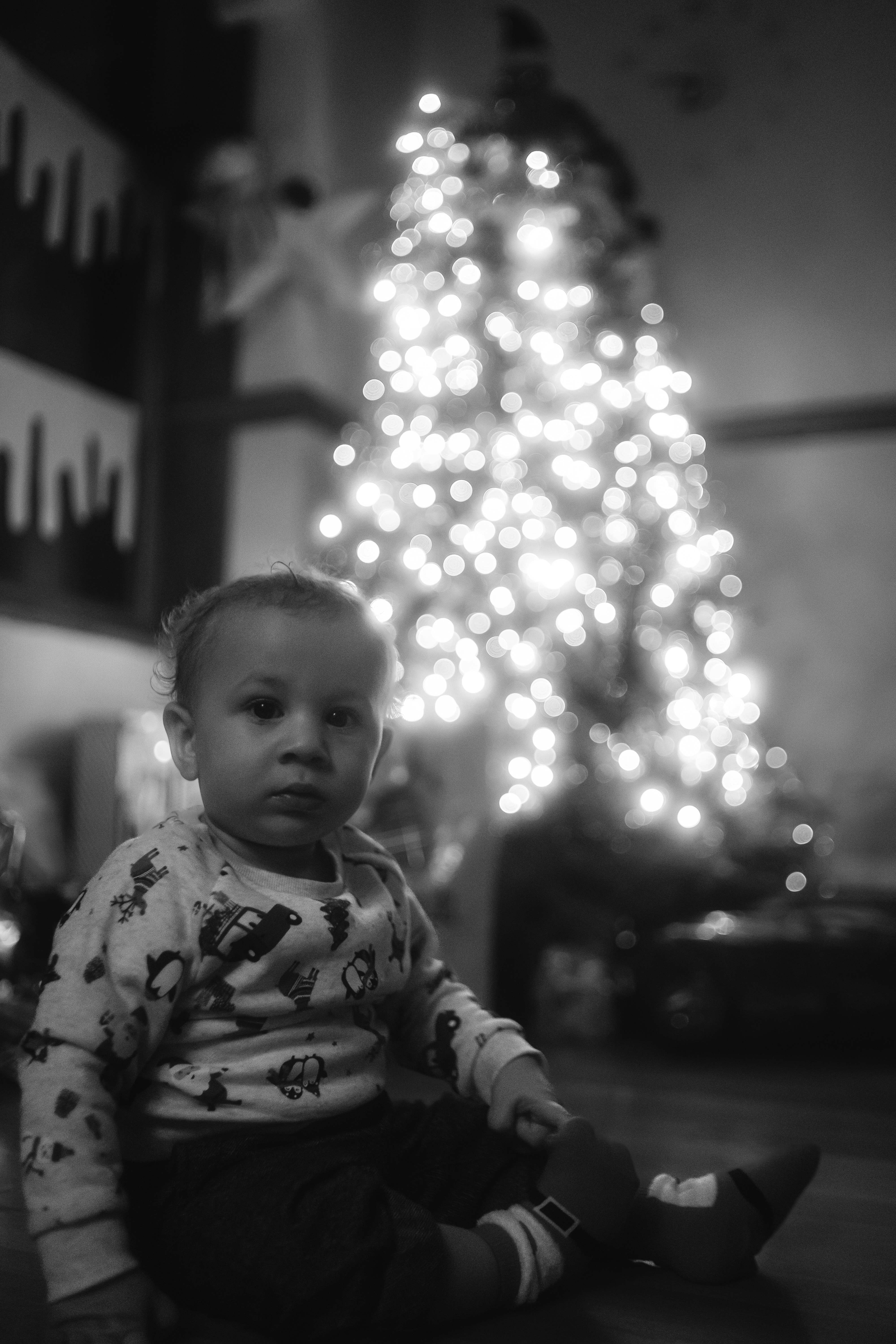 a baby sitting in front of a christmas tree