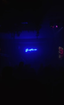 Close-up of a glowing electric blue neon sign reading 'Aria Creator Lab' against a dark slate wall.