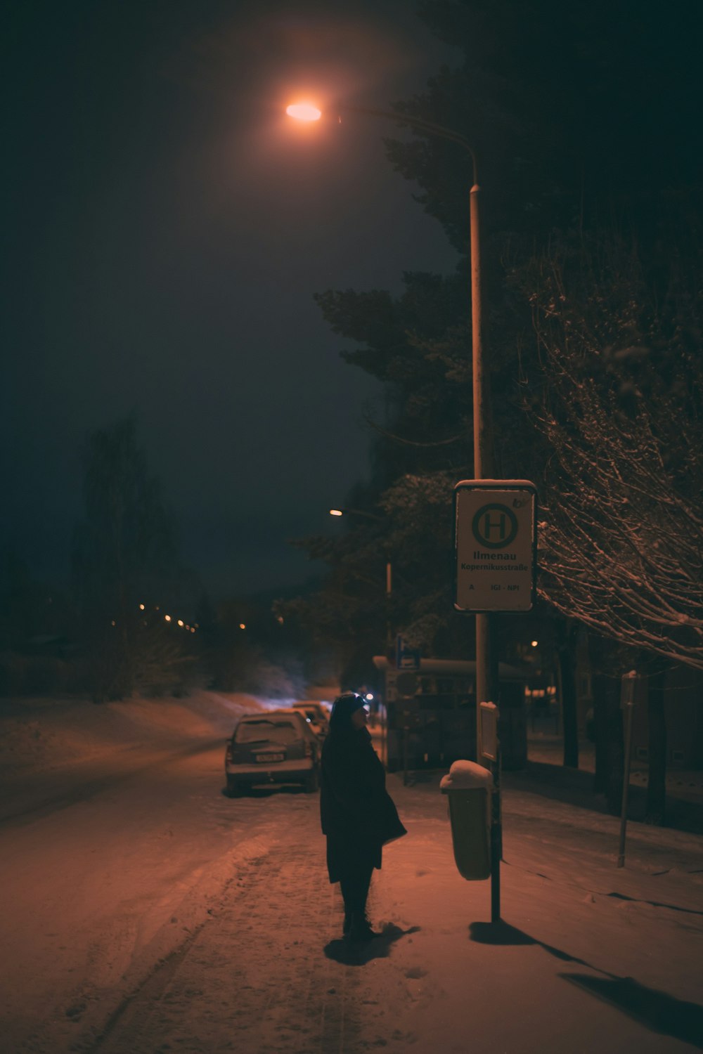a woman walking down a snow covered street at night