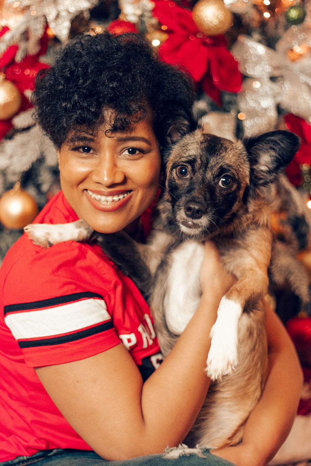 a woman holding a dog in front of a christmas tree