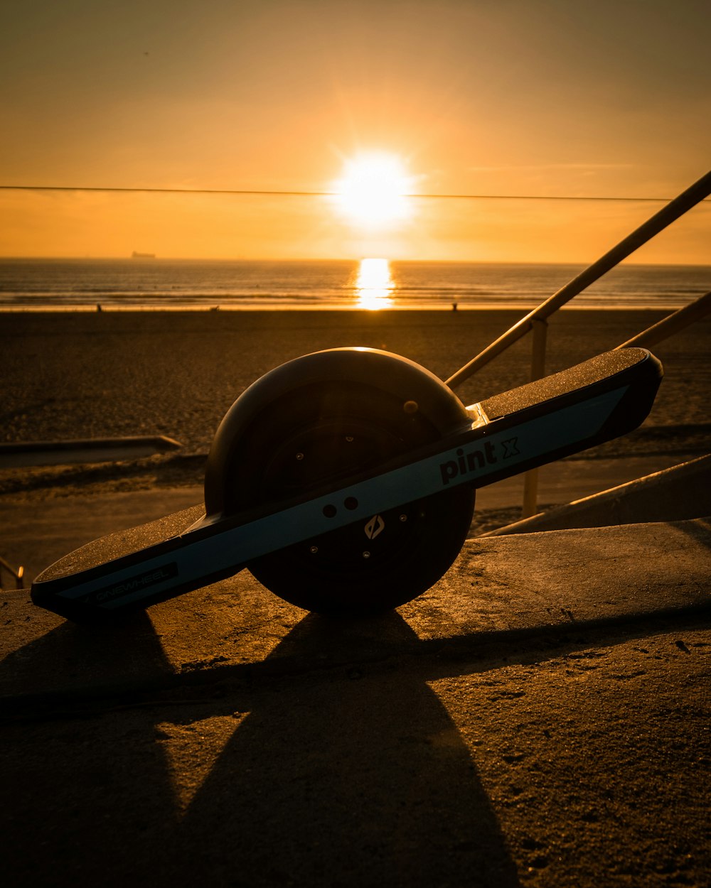 the sun is setting over the beach with a pair of skis on the ground